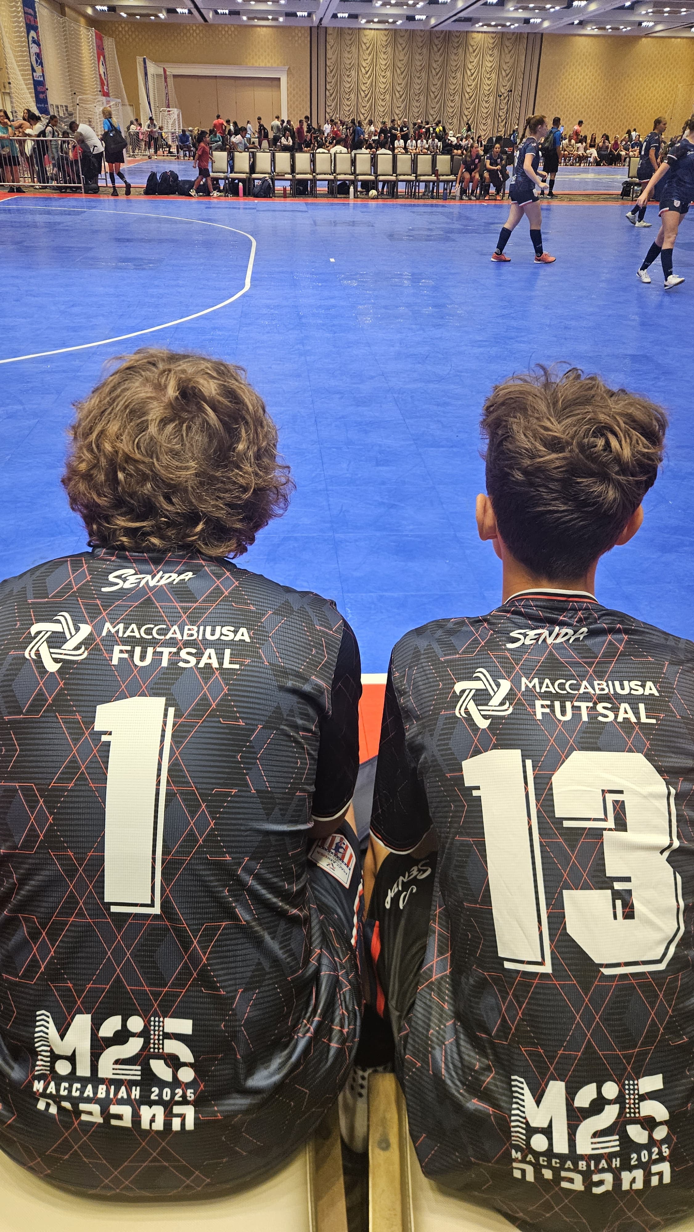 Two individuals wearing Maccabi USA Futsal jerseys on a blue indoor sports court in the US Futsal event in Las Vegas.