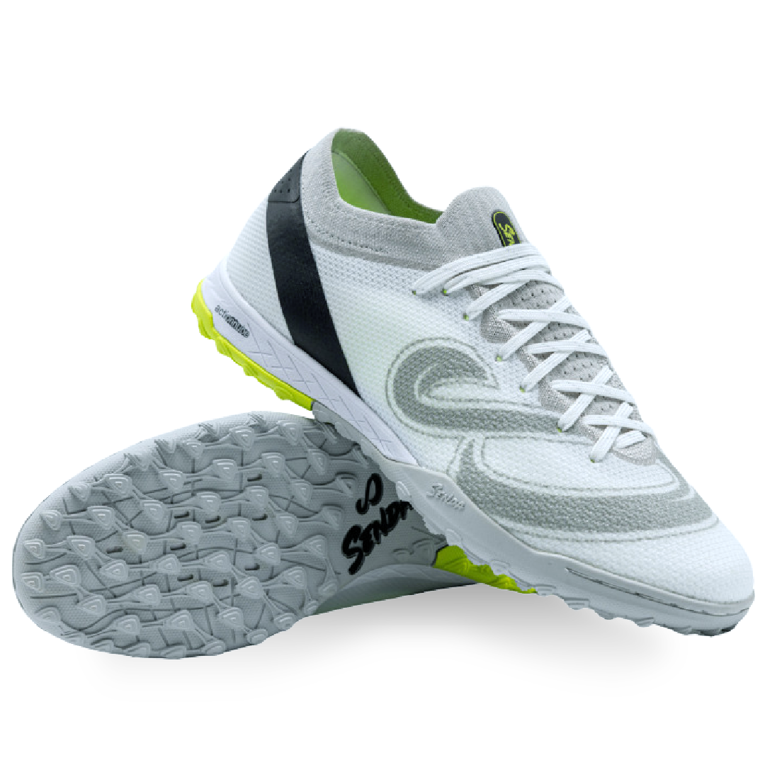 White turf shoe with black and green accents on a white background