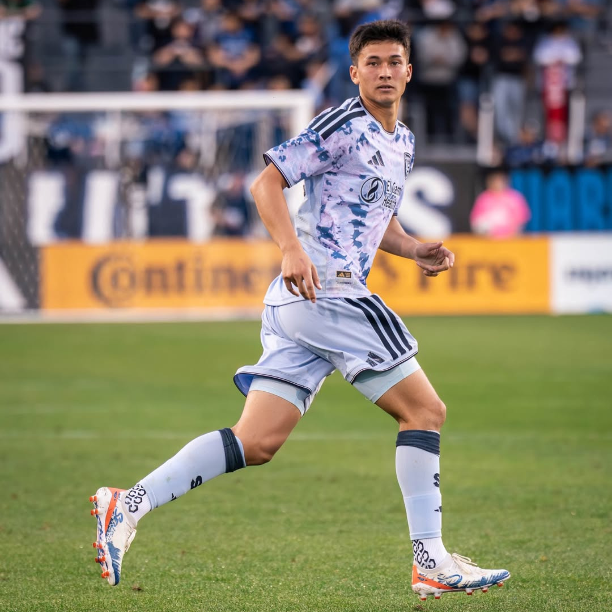 Soccer player in action on a field with a blurred crowd in the background