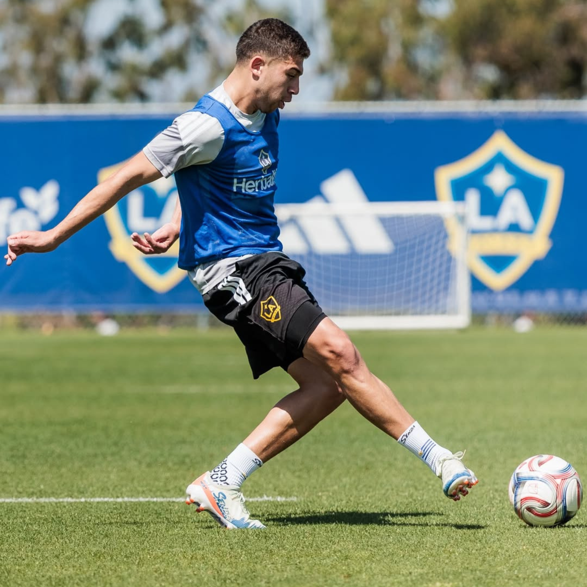 Soccer player in action on a field with a blue banner in the background