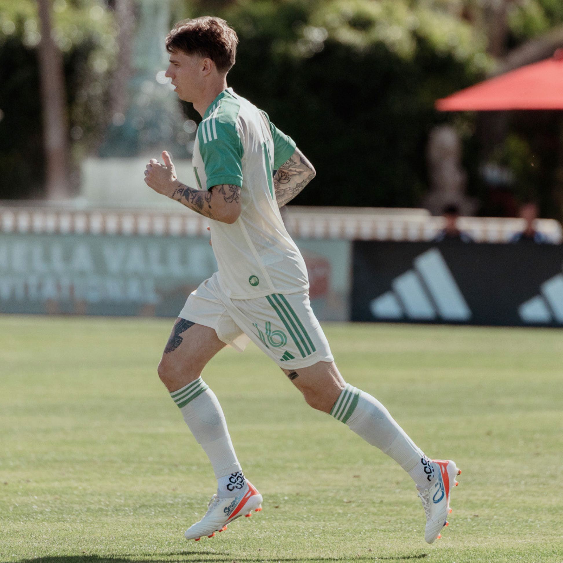 Soccer player in a green and white uniform running on a field with blurred background