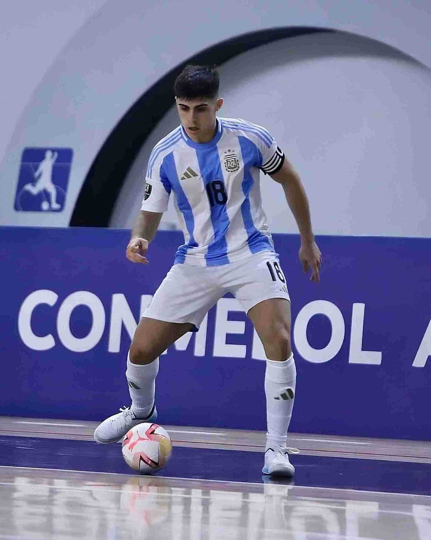 Futsal player playing on a court with 'CONMEBOL' branding.