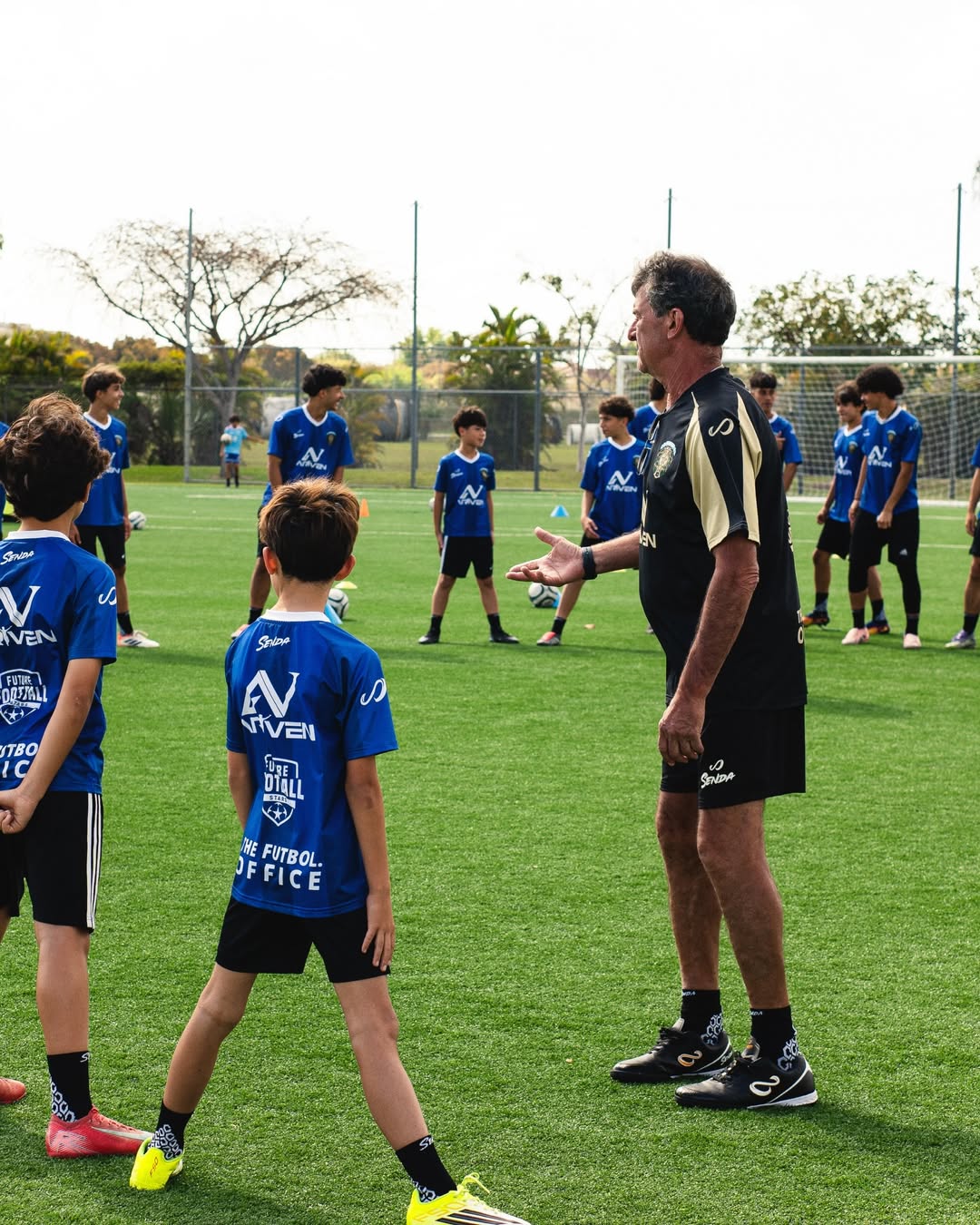 Mario Kempes interacting with young soccer players on a field