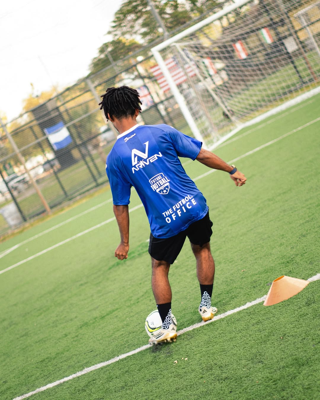 Person in a blue sports Senda jersey on a soccer field at Mario Kempes Soccer Clinic.