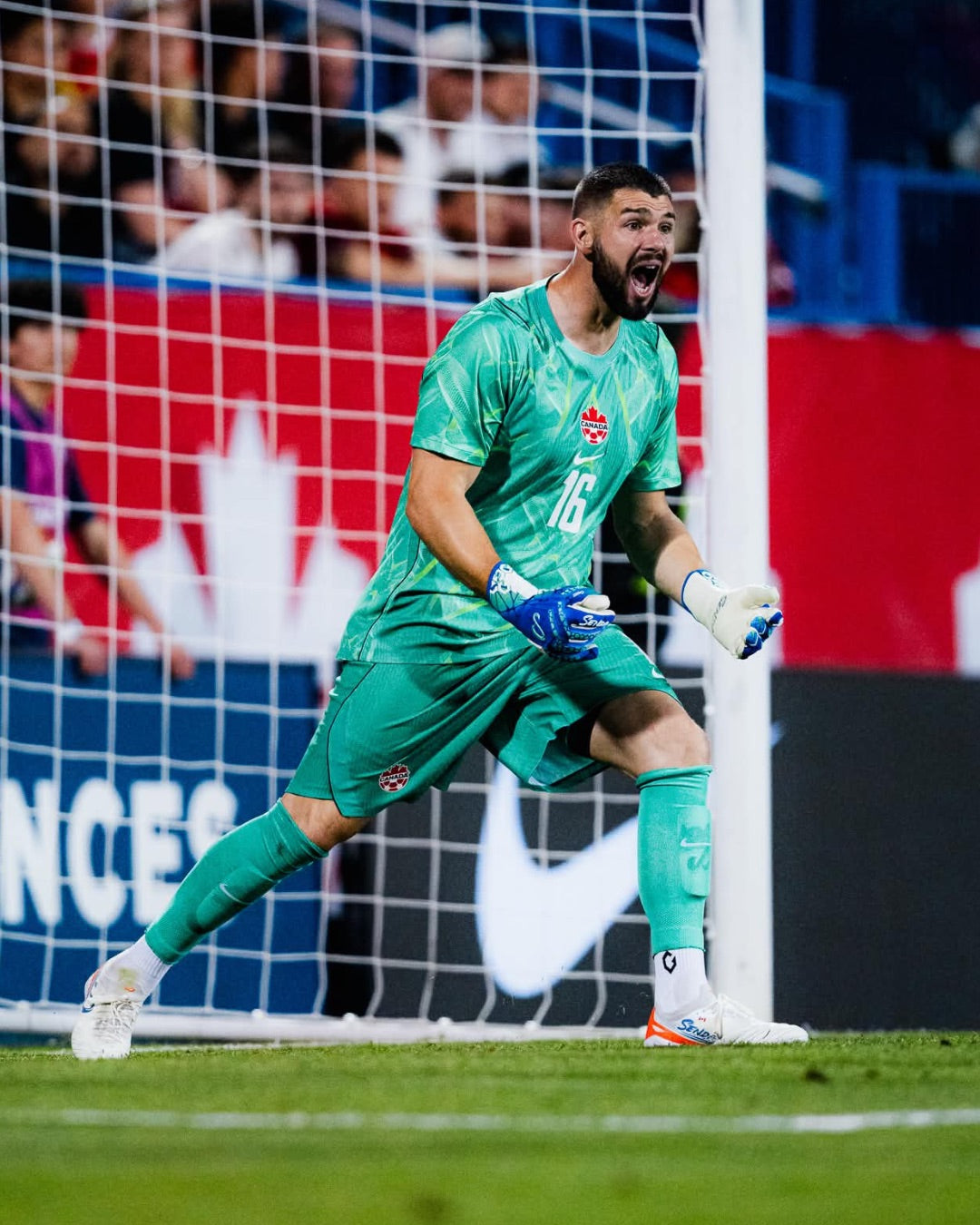 Soccer goalkeeper Max Crepeau in green uniform with number 16 on a field, with a blurred crowd in the background.