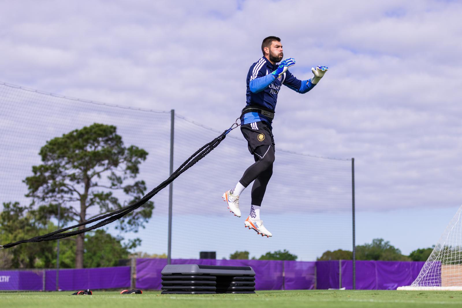 Person using resistance bands on a sports field with trees and sky in the background