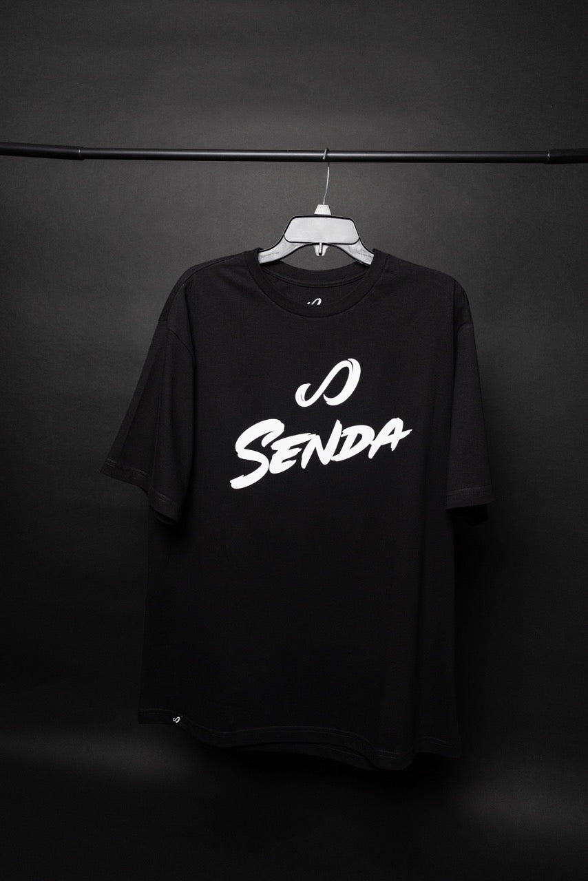 Black t-shirt with 'O Senda' text on a hanger against a dark background. Senda Lifestyle Apparel Collection
