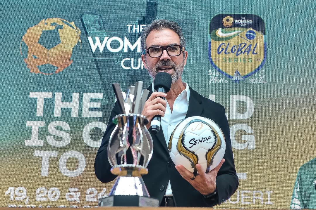 Man holding a trophy and a ball with event branding in the background