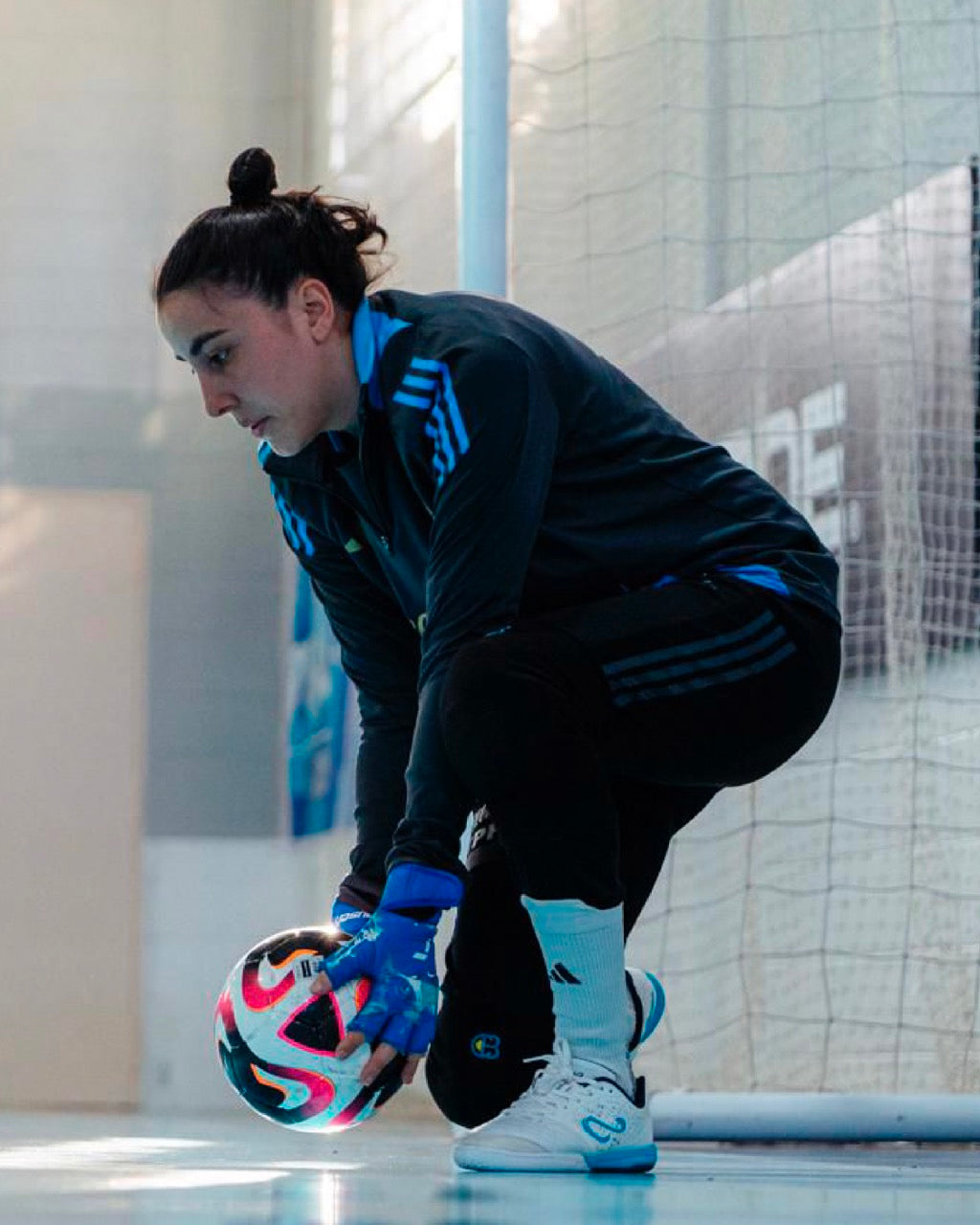 Person in athletic wear with a colorful ball on a futsal court