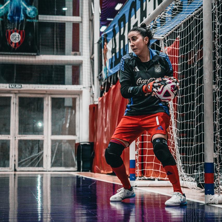 Goalkeeper in action inside an indoor futsal facility.
