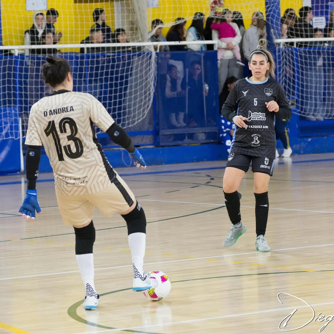 Two soccer players on a court with a goal in the background