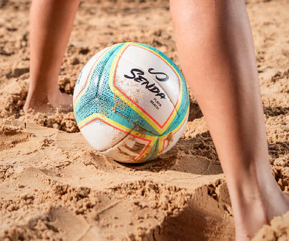 Colorful beach soccer ball on sand with 'Senda' branding