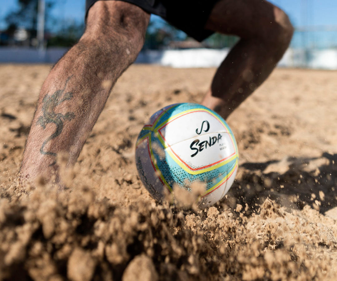 Colorful beach soccer ball with 'Senda' branding on a sandy surface.