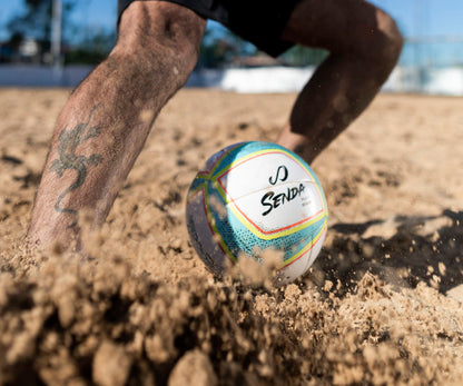Colorful beach soccer ball with 'Senda' branding on a sandy surface.