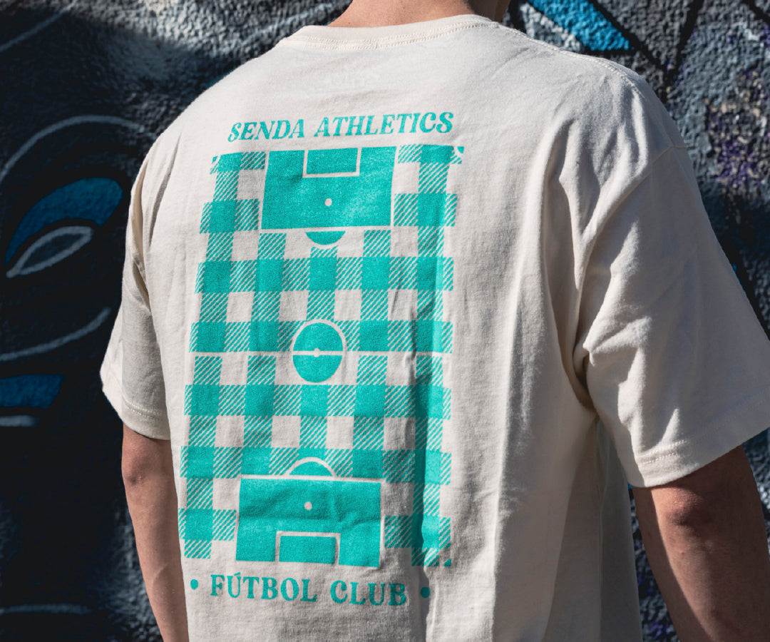Person wearing a t-shirt with 'Senda Athletics Fútbol Club' design on the back.