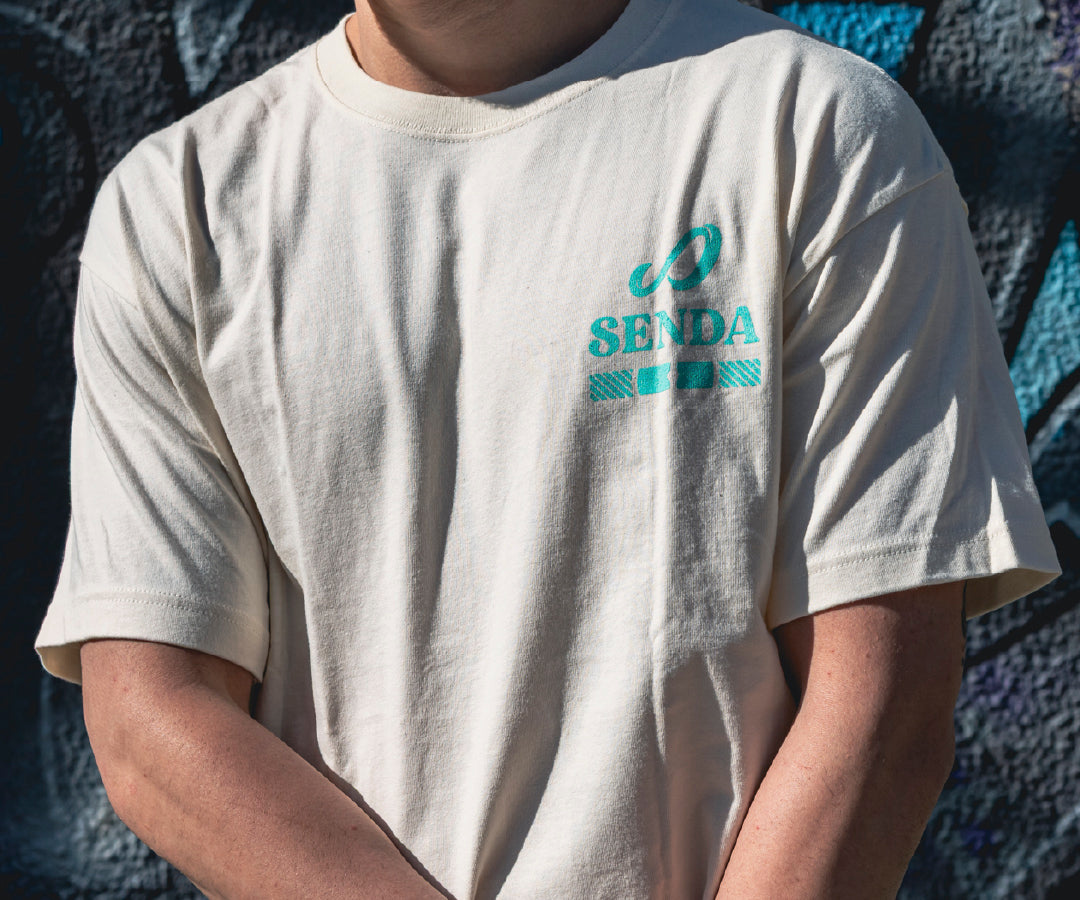Person wearing a white t-shirt with a blue logo against a dark textured background