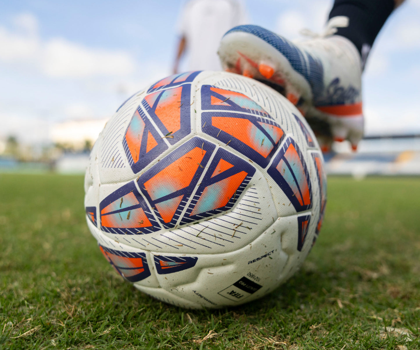Soccer ball with orange and blue patterns on a grass field