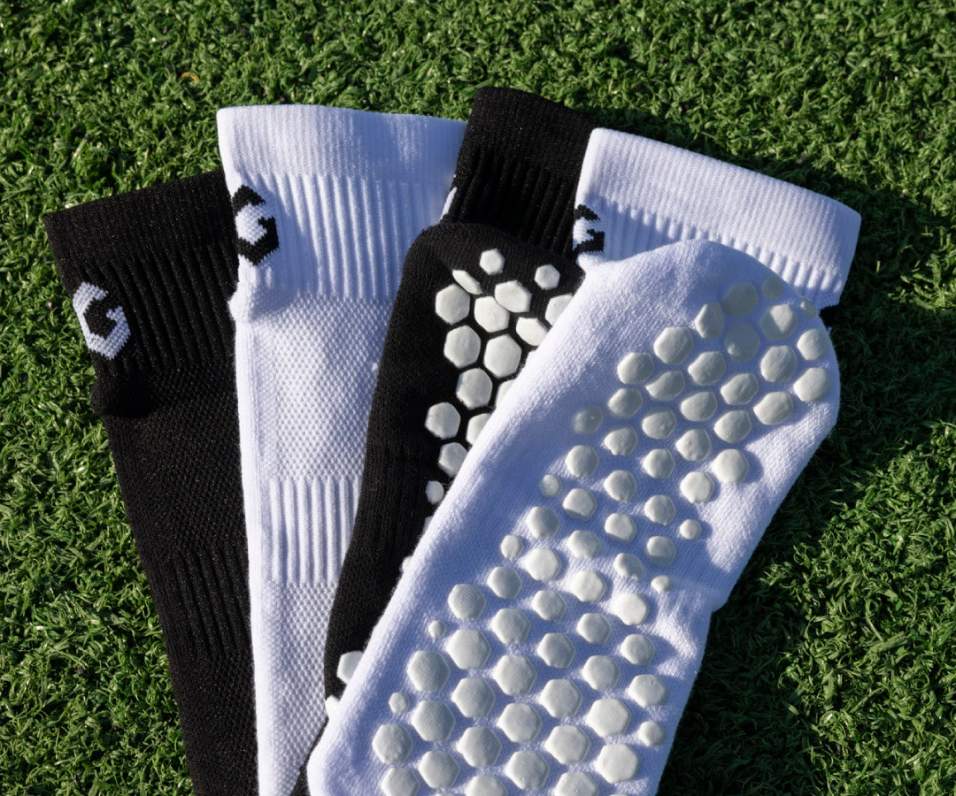 Three pairs of ankle grip socks with textured soles on a turf background