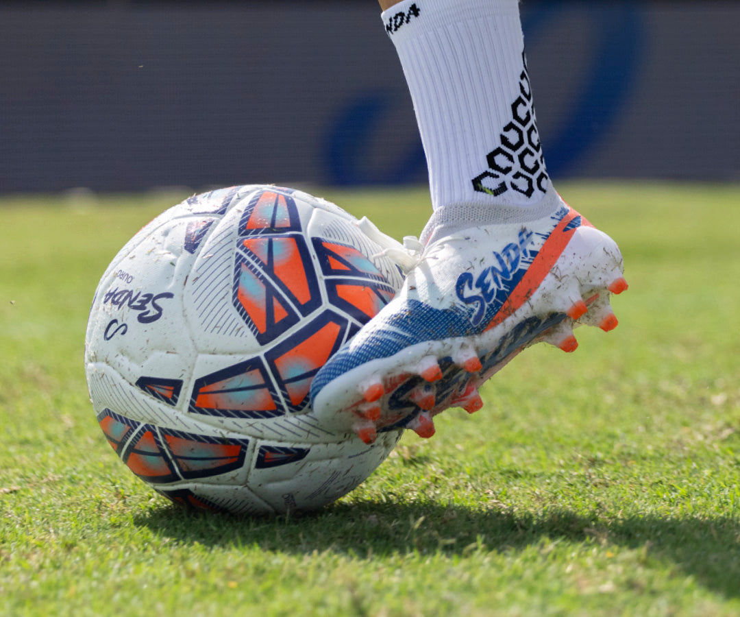 Senda Soccer shoe kicking a soccer ball on grass
