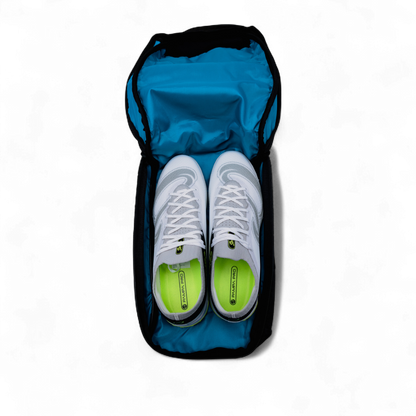 White sneakers with green soles in a blue shoe bag on a white background
