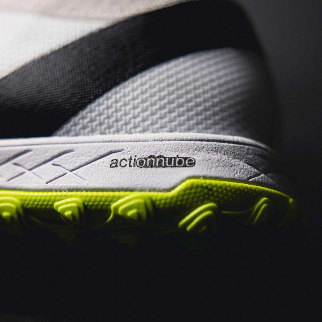 Close-up of a shoe sole with 'actionnube' branding on a dark background.Turf Shoes.
