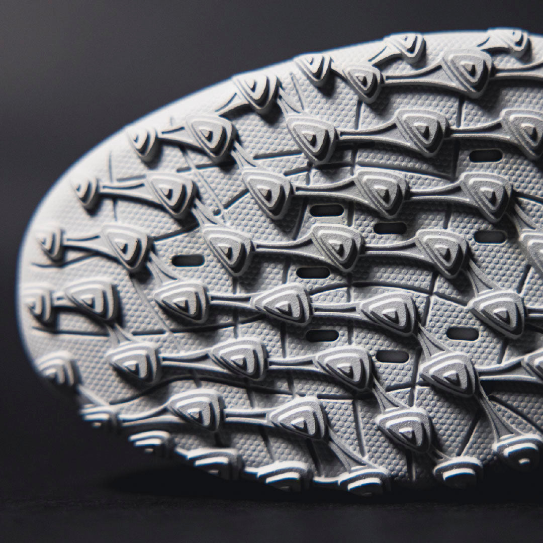 Close-up of a textured shoe sole with a dark background.Turf Shoes.