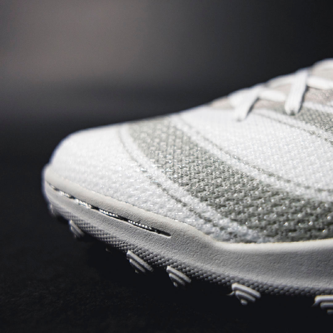 Close-up of a gray athletic shoe on a black background.Turf Shoes.
