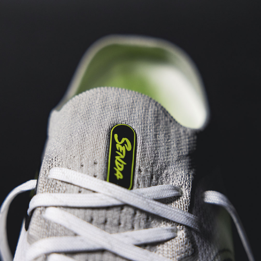 Gray sneaker with a brand logo on a black background.Turf Shoes.